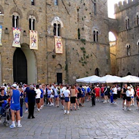 Piazza tra gli antichi palazzi di Volterra piena di podisti